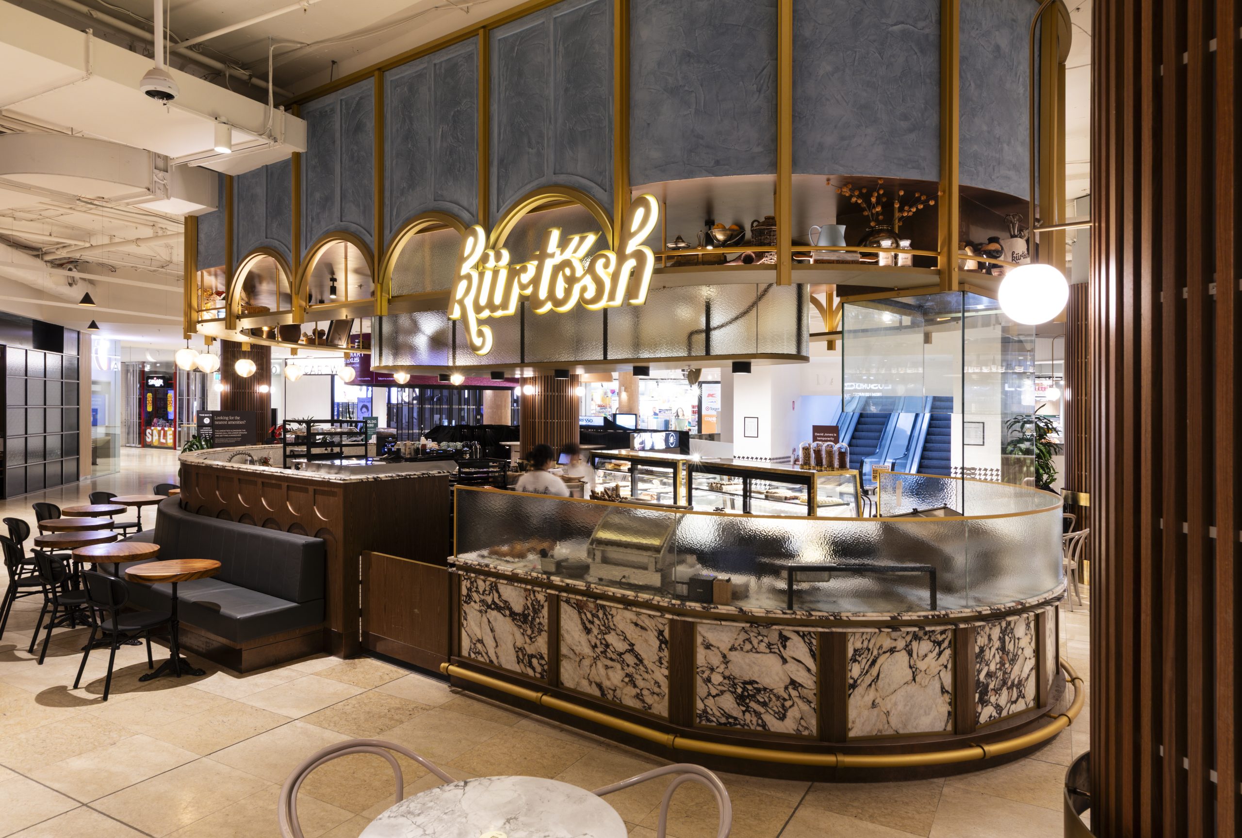 A luxury commercial bakery kiosk for Kürtősh inside a shopping center, featuring intricate curved marble counters and overhead custom framing designed with Pytha 3D CAD software.