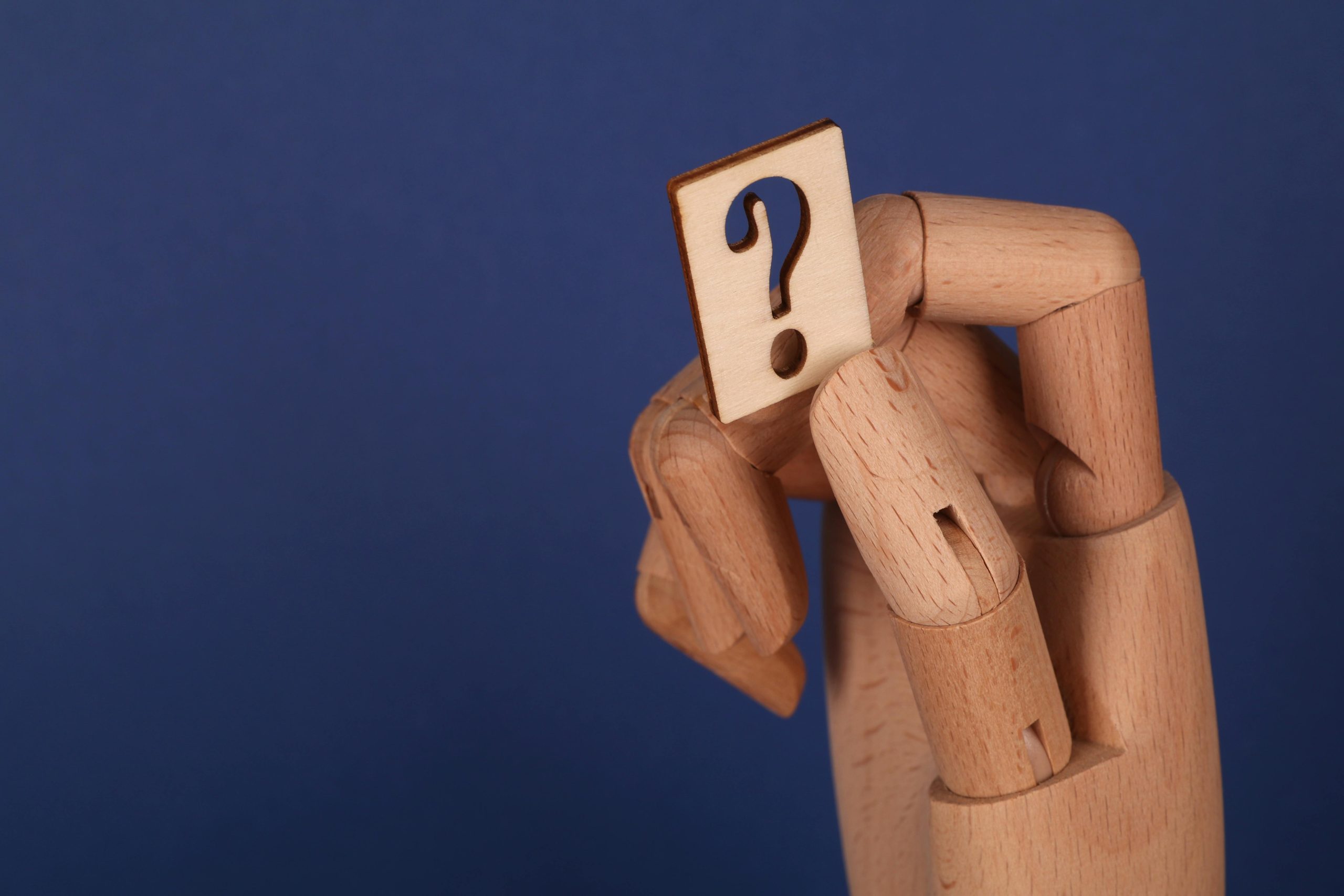 A Question Mark Held By a Wooden Hand | Joinery Designer | Inline Consulting