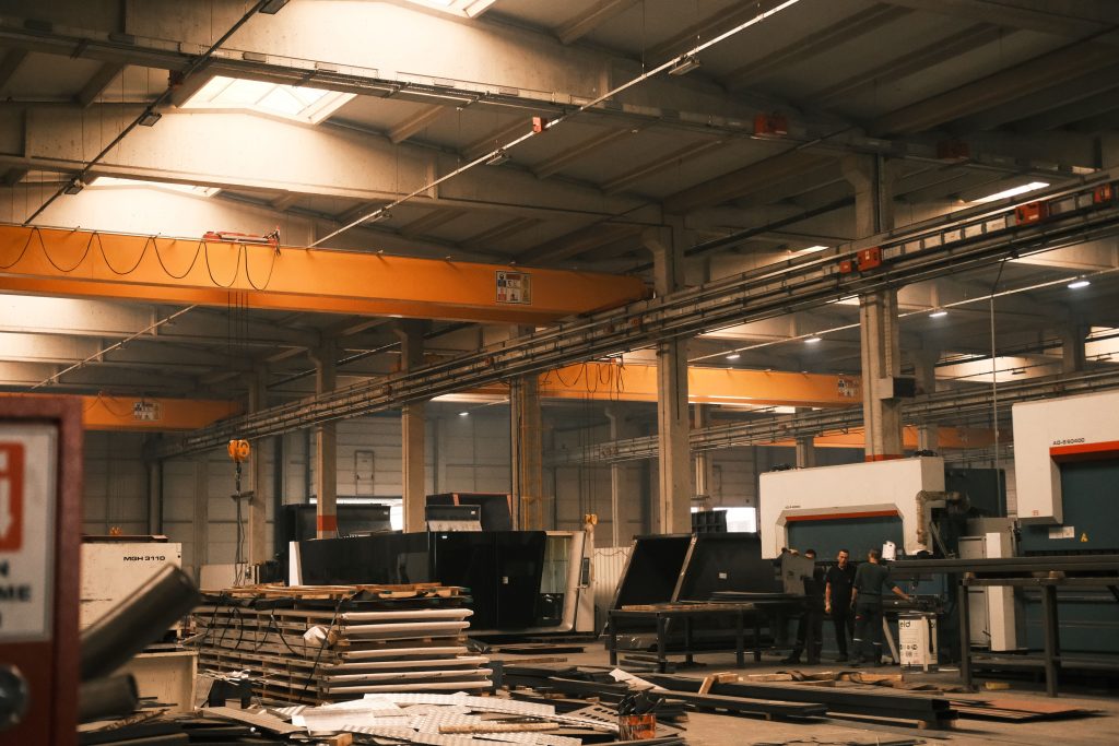A large manufacturing plant floor with machinery and cranes, demonstrating structural projects requiring remote design support.