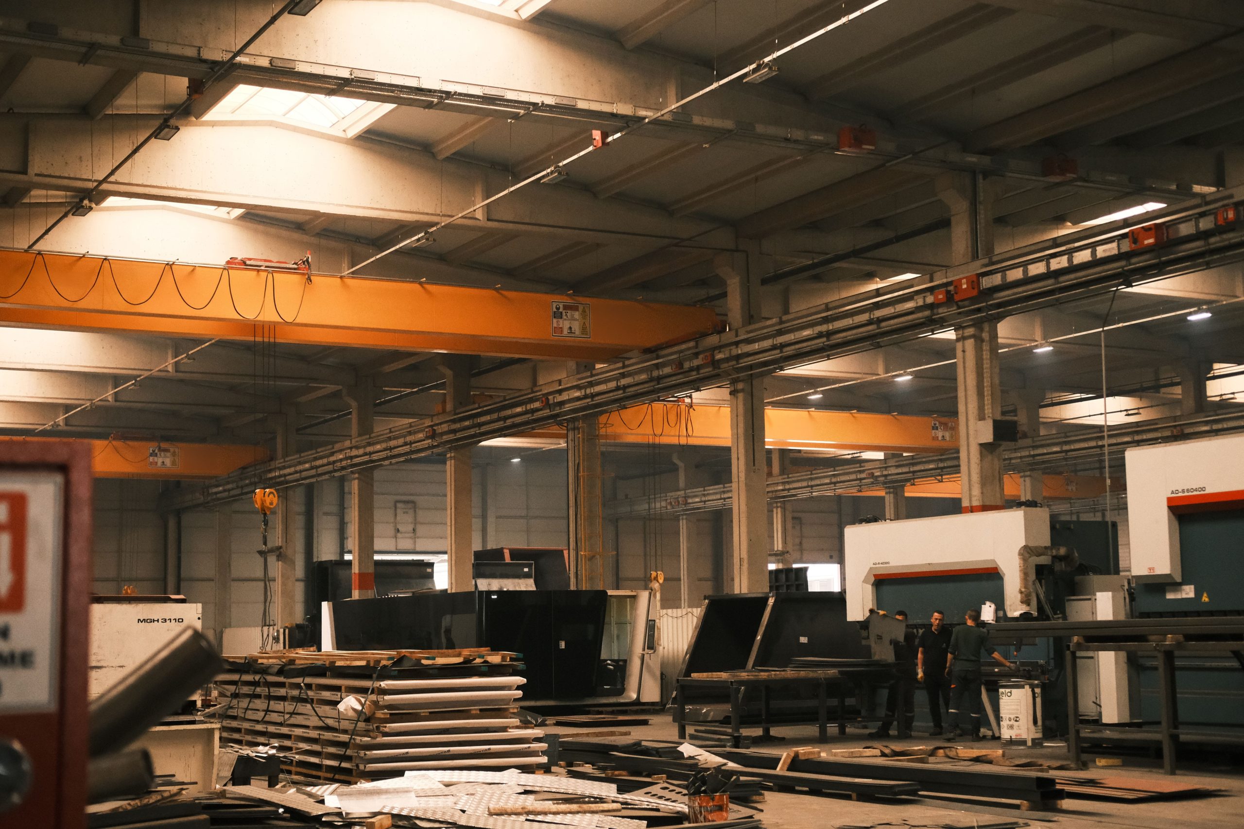 A large manufacturing plant floor with machinery and cranes, demonstrating structural projects requiring remote design support.