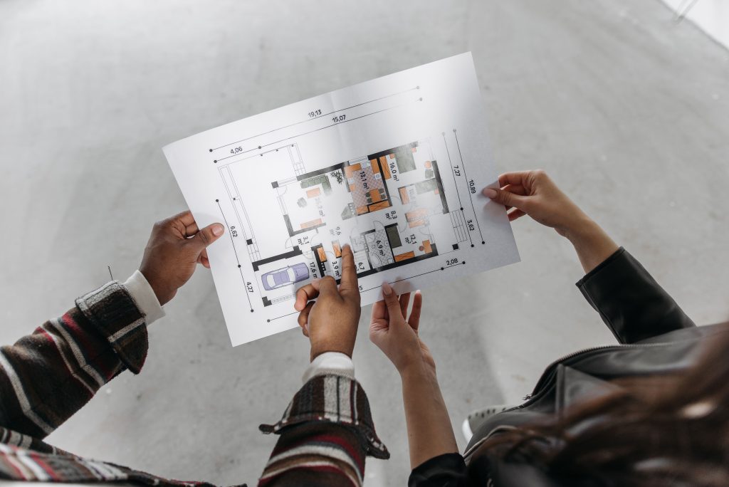 Two professionals reviewing a detailed architectural floor plan blueprint, representing strategic planning and business innovation at Inline Consulting.