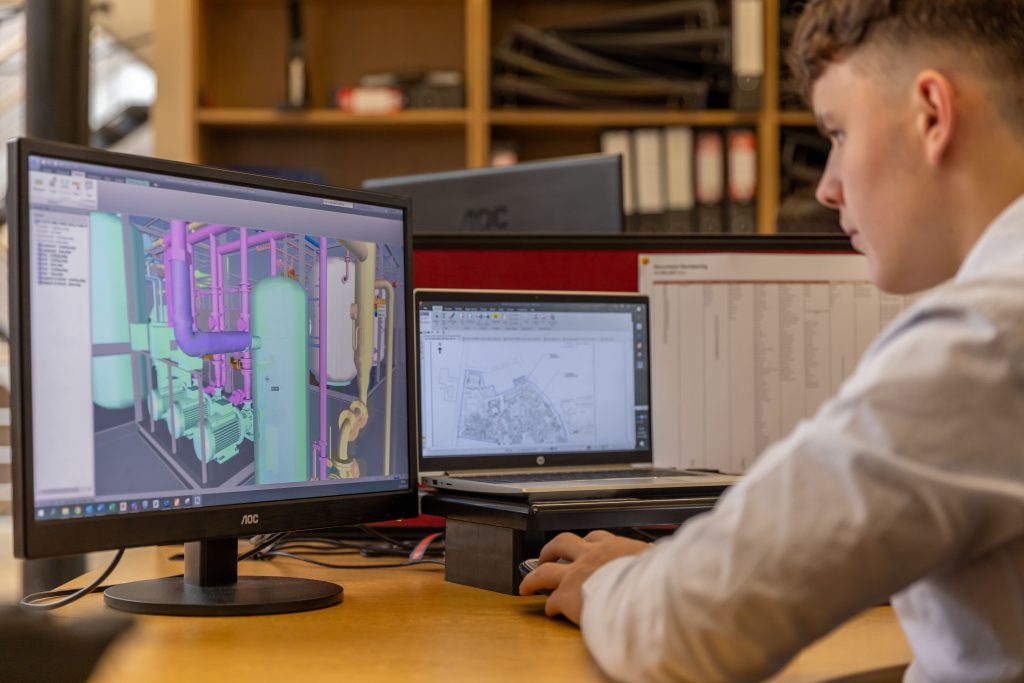 CAD operator analyzing a complex 3D technical model on a dual-monitor workstation, comparing PYTHA vs CAD software performance for industrial design.